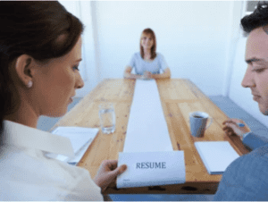 A man and woman sitting at a table with a resume in front of them.