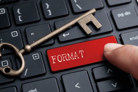 A person holding a red key on a keyboard with the word format on it.
